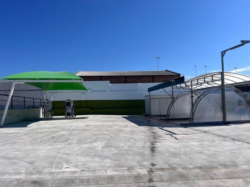 Carpa textil verde instalada sobre una zona de autolavado con equipos de lavado para coches.