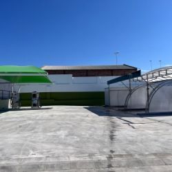 Carpa textil verde instalada sobre una zona de autolavado con equipos de lavado para coches