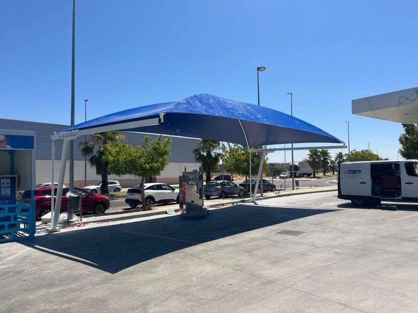 Carpa de lona vista desde un lateral, instalada sobre una zona de lavado de coches